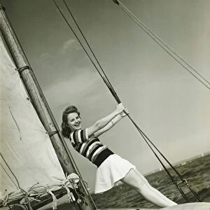 Young woman holding rigging on yacht, (B&W)
