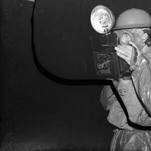 A press photographer in a ARP ( Air Raid Precautions ) gas suit, taking pictures