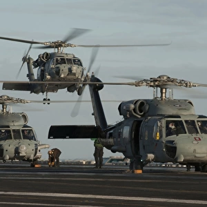 Military helicopters land on the flight deck of USS Carl Vinson