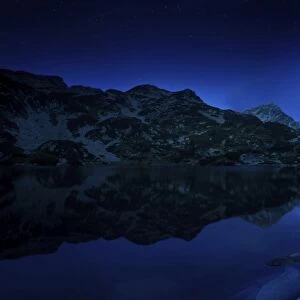 Moon rising over tranquil lake and mountains in Pirin National Park, Bulgaria