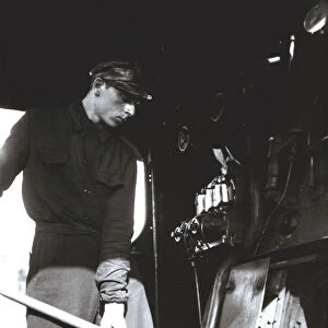 Stoker putting coal to a steam train engine