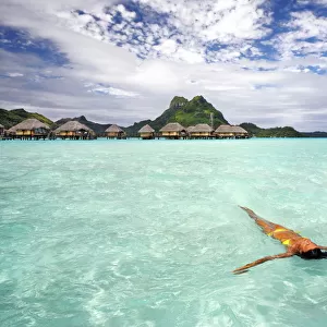 French Polynesia, Tahiti, Bora Bora, Woman Floating In Water Near Resort