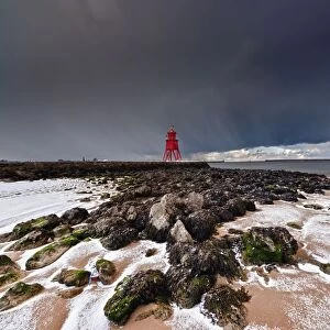 A Red Lighthouse Along The Coast Under A Stormy Sky; South Shields, Tyne And Wear, England