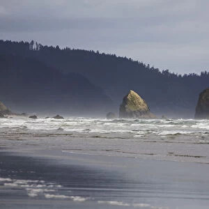 Rock Formations In The Ocean With Waves On The Beach; Cannon Beach, Oregon, United States of America