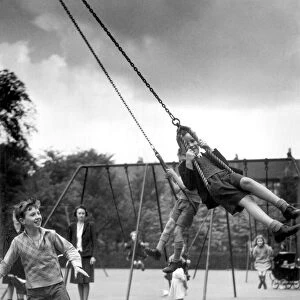 Two boys playing on swings in the playground. 10th July 1942