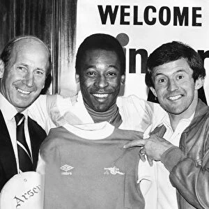 Brazilian footballer Pele with John Hollins and Bobby Charlton size up an Arsenal shirt