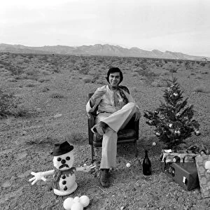 Engelbert Humperdinck sitting in a chair with a Christmas tree