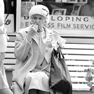 An old lady enjoying fish and chips during a day out to the beach at Trecco Bay