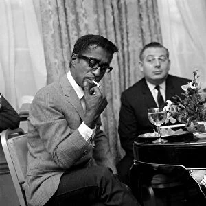 Sammy Davis Jnr. lights a cigarette in a London restaurant whilst having lunch with
