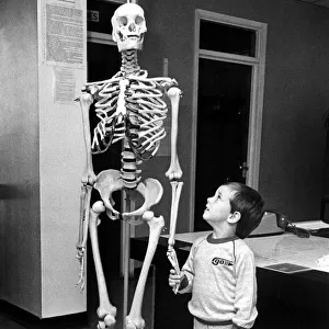 A small child holding hands with a skeleton on 10th September 1985