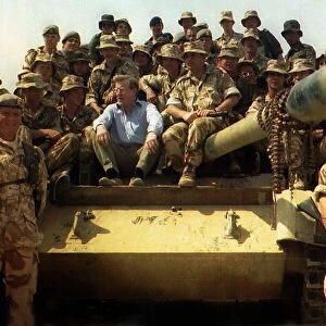 Tom King MP sits on a army tank with a group of soldiers