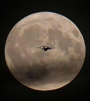A passenger plane is seen with the full moon behind as it begins its final landing
