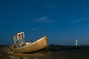 Shingle Prints: Abandoned fishing boat on shingle beach illuminated by torchlight at night
