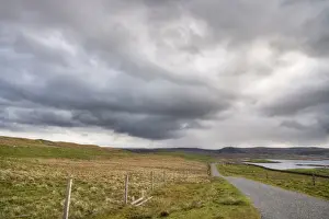 Stormy Prints: Approaching stormclouds over single track road and coastline