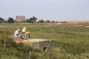 World Prints: Artist sitting on World War 2 pill box looking over Oxley marsh at Shingle Street, Suffolk