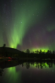 Aurora Borealis and stars over lake at night, Muonio, Lapland, Finland, September