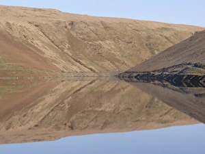 Banks of reservoir reflected in water, Claerwen Dam, Elan Valley, Powys, Wales, january