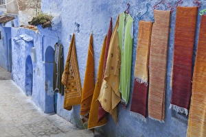 Moroccan Prints: Blue houses and textiles for sale in alley of city, Chefchaouen, Morocco, april