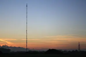 Radio Prints: Broadcasting and telecommunication facility with guyed steel lattice mast silhouetted at sunset