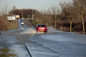 Flood Prints: Car driving through flooded rural road