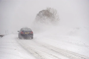 Cars Prints: Car travelling along rural road during severe snowstorm