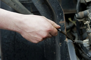 Checking oil level in tractor engine using dipstick, England, october