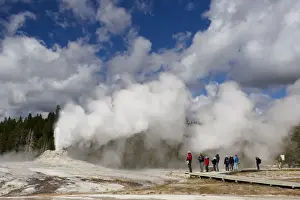 Boardwalks Prints: Cone-type geyser erupting, with tourists walking from boardwalk