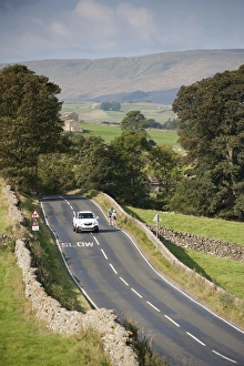 : Country road with car passing cyclists, near Hawes, Wensleydale, Yorkshire Dales N. P
