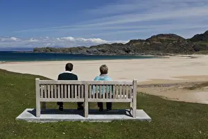 Woman Prints: Couple sitting on bench overlooking coastline with sandy beach