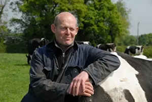 Jobs Prints: Dairy farmer Steve Hook with Friesian cows in herd on organic dairy farm