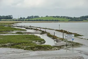 Track Prints: Danger, Beware of fast tides, hidden channels and quick sands warning sign beside road from coastal village