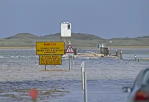 Dangerous Prints: Danger, do not proceed when water reaches causeway sign on causeway underwater at high tide