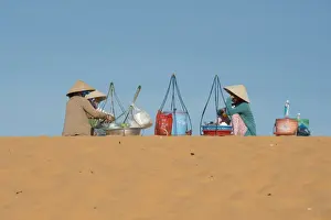 : Drink sellers in conical hats, sitting on coastal sand dunes
