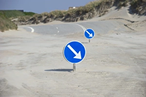 Sandy Prints: Driving direction signs on sandy beach at start of road