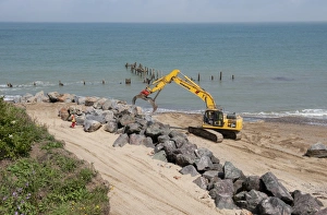 Defence Prints: Excavator on beach, repairing sea defences with boulders