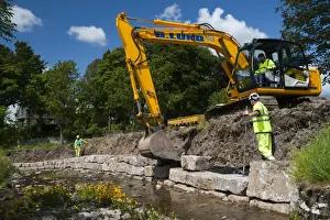Excavator improving stream bank to help prevent flooding, Cumbria, England, june