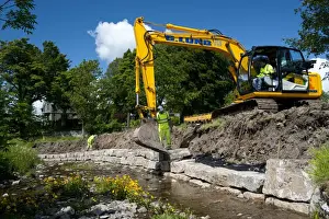 Excavator improving stream bank to help prevent flooding, Cumbria, England, june