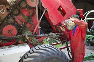 Jobs Prints: Farmer greasing chain on round baler, Sweden, july