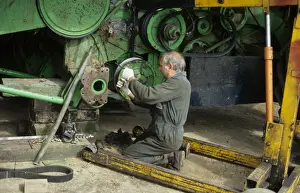 Repairs Prints: Farmer repairing combine harvester clutch at harvest time, West Sussex, England, august