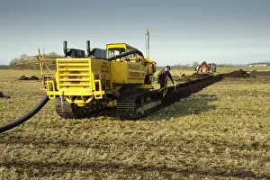 Field drainage, continuous pipe laying machine working in arable field, Pilling, Lancashire, England, march