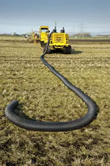 Field drainage, continuous pipe laying machine working in arable field, Pilling, Lancashire, England, march