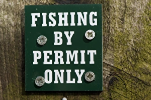 Private Prints: Fishing By Permit Only sign on post beside lake, England, april