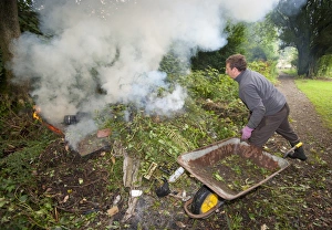 Gardener burning garden rubbish on bonfire, Chipping, Lancashire, England, august
