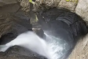 Erosion Prints: Glacier waterfall flowing over eroded rocks inside mountain