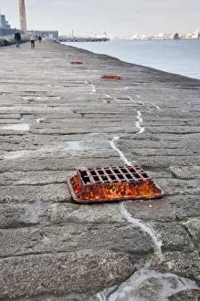Protects Prints: Grate covering glass plate measuring rate of cracking in granite sea wall protecting harbour entrance