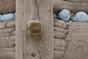 Groynes, abstract view of rusty bolt and pebbles stuck in weathered timber, West Runton, Norfolk, England