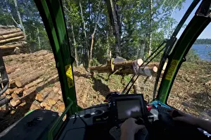 Interior of John Deere 1010E Forwarder loading logs onto timber barge, Archipelago Sea, Baltic Sea, Sweden, june