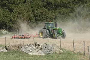 John Deere 4455 tractor pulling Vaderstad cultivator, cultivating arable seedbed, in dusty ploughed field, Sweden