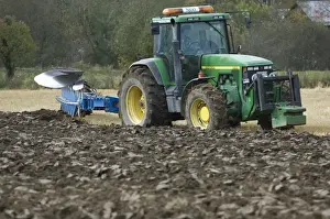 John Deere 8400 tractor pulling eight furrow reversible plough, ploughing stubble field, Sweden, autumn