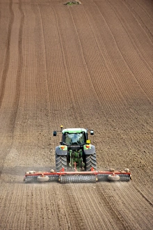 John Deere tractor pulling soil press, rolling seedbed in arable field, Kelso, Scottish Borders, Scotland, september